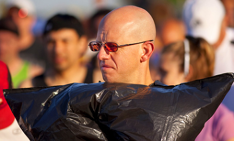 A runner keeps warm by wearing a black garbage bag before the race.