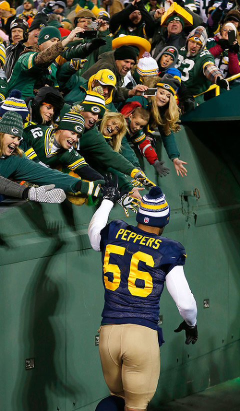 Green Bay Packers outside linebacker Julius Peppers high fives fans as he runs off the field.