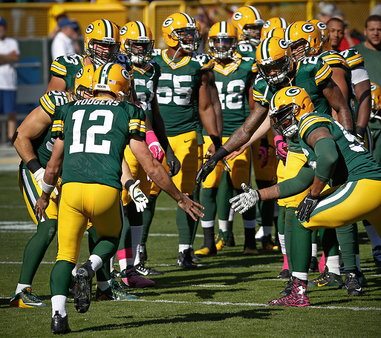 Green Bay Packers quarterback Aaron Rodgers low fives his teammates.