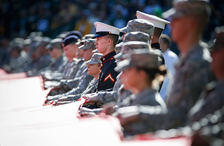 Service men and women hold a large American flag during the national anthem.