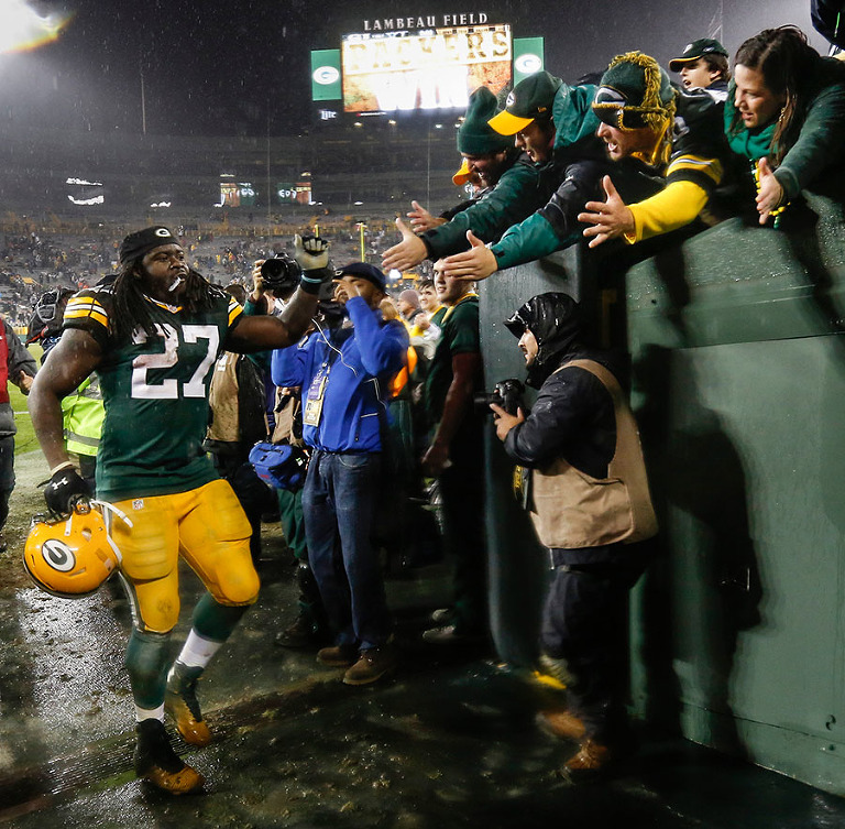 Green Bay Packers running back Eddie Lacy celebrates with fans as he walks off the field.