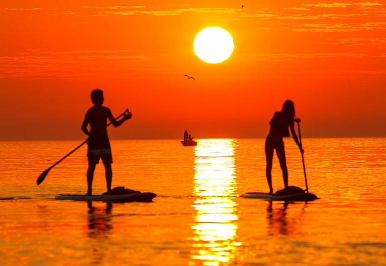 Sunrise stand up paddle boarding near the Manitowoc Lighthouse on Lake Michigan in Manitowoc, Wisconsin.