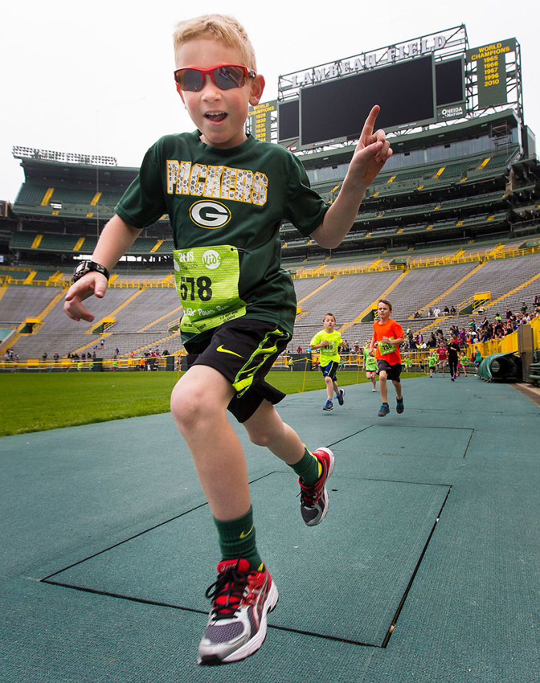 A young runner shows his excitement as he takes a lap around Lambeau Field during the kids run of the Green Bay Cellcom marathon weekend.