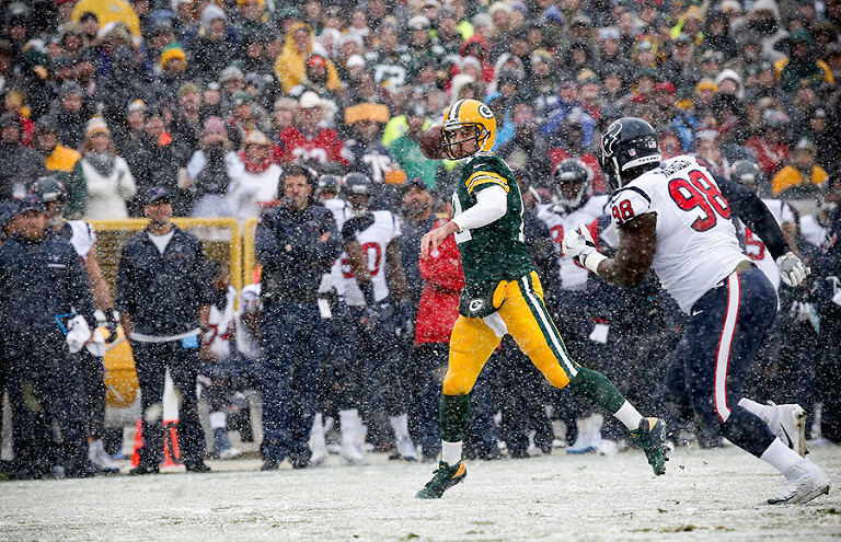 Green Bay Packers quarterback Aaron Rodgers throws downfield after scrambling out of the pocket.
