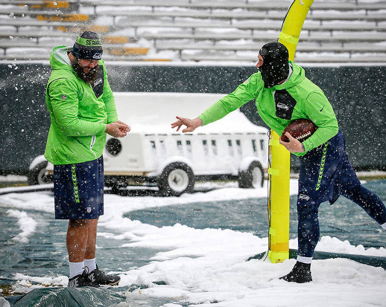 Seattle Seahawks' Justin Britt hits Mark Glowinski with a snowball as they head out on to the field to check the conditions before warmups.