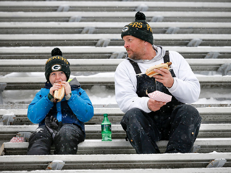 Lee Kuehl enjoys a brat with his son Jake brats inside Lambeau Field.