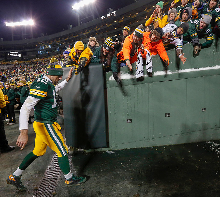 Green Bay Packers quarterback Aaron Rodgers high fives fans as he walks off the field.